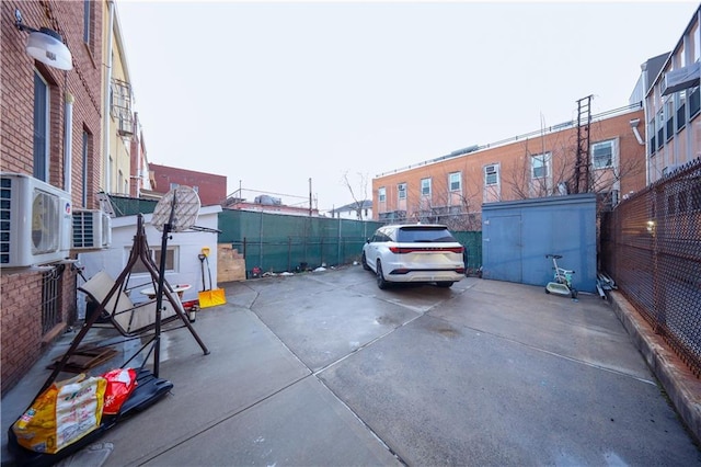 view of parking with ac unit and fence