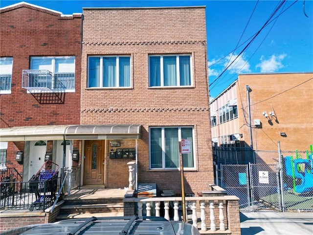 view of front of property featuring brick siding, fence, and a gate