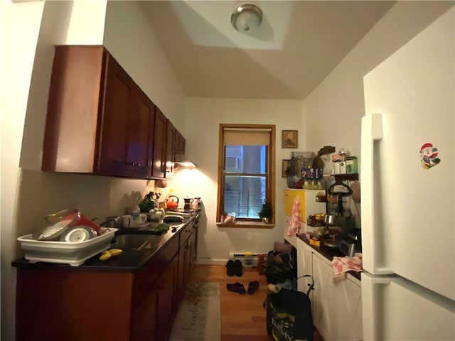 kitchen featuring dark countertops, a sink, and wood finished floors