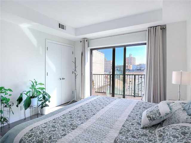 bedroom with access to exterior, a view of city, a closet, and visible vents