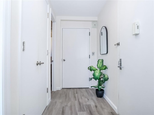 hallway with light wood finished floors and baseboards