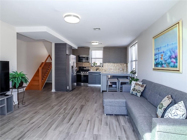 living area with light wood finished floors, stairs, and visible vents