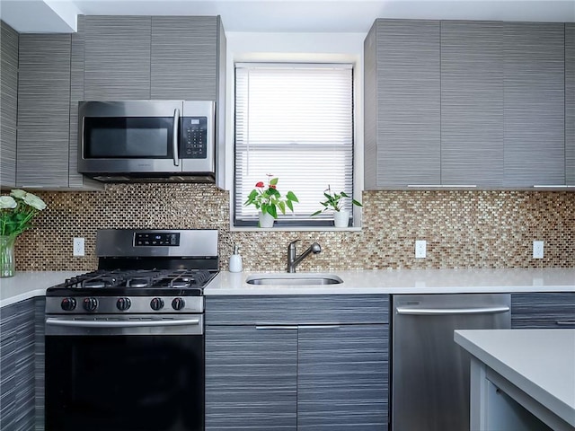 kitchen with stainless steel appliances, light countertops, decorative backsplash, a sink, and modern cabinets