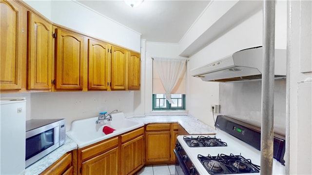 kitchen with light countertops, stainless steel microwave, white gas range oven, and a sink