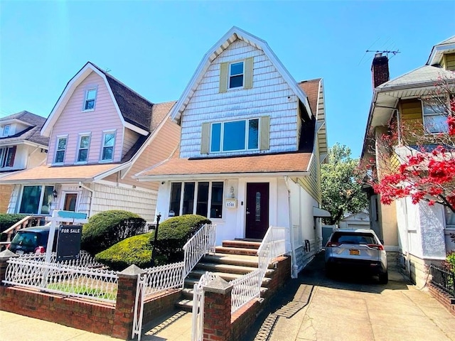 view of front facade featuring a fenced front yard, a gambrel roof, and a shingled roof