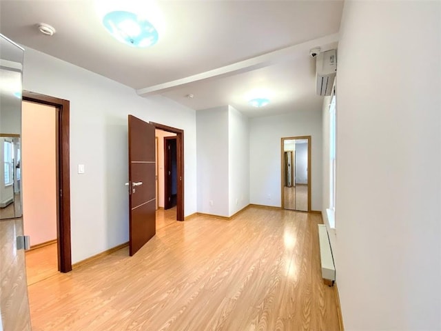 empty room with light wood finished floors, baseboards, and a smoke detector