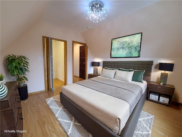 bedroom with wood finished floors, lofted ceiling, and baseboards
