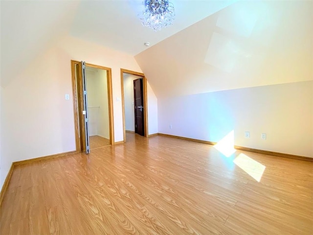 bonus room with vaulted ceiling, light wood-style flooring, baseboards, and a chandelier