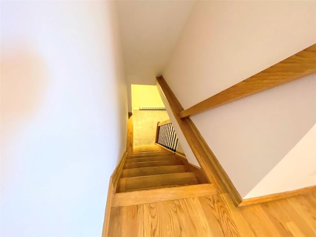 stairway with wood finished floors and vaulted ceiling