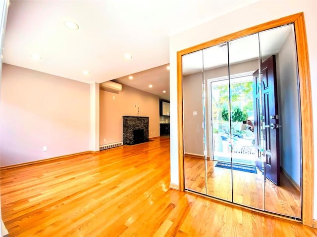 entryway with wood finished floors, a fireplace with flush hearth, recessed lighting, and baseboards