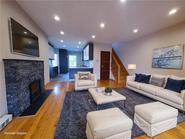 living room with stairs, light wood finished floors, recessed lighting, and a fireplace
