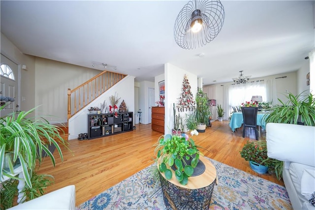 living area with stairs, wood finished floors, and a chandelier