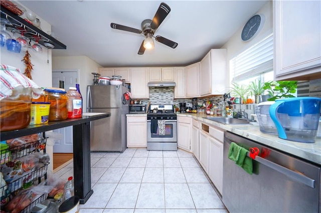 kitchen with decorative backsplash, ceiling fan, light countertops, a sink, and appliances with stainless steel finishes
