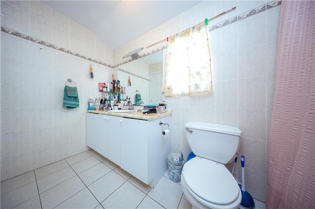 bathroom featuring tile walls, toilet, vaulted ceiling, vanity, and tile patterned floors