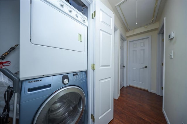 clothes washing area featuring laundry area, stacked washer / dryer, dark wood-style flooring, baseboards, and attic access