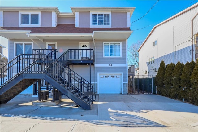 view of front facade featuring stucco siding, a porch, concrete driveway, stairway, and a garage