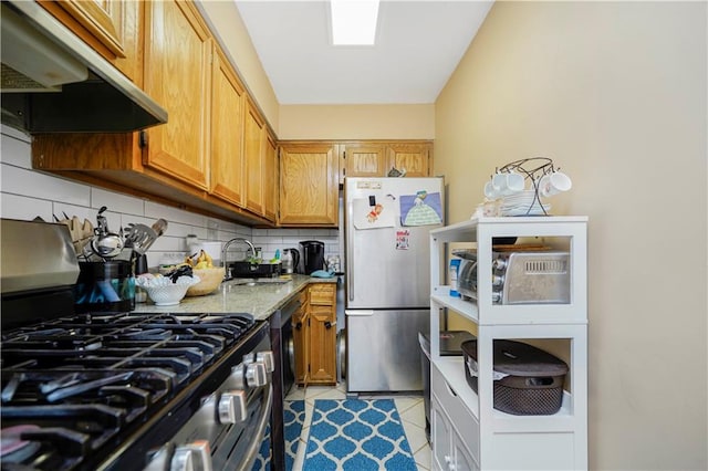 kitchen featuring light tile patterned flooring, a sink, under cabinet range hood, appliances with stainless steel finishes, and backsplash