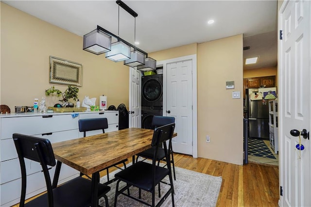 dining space featuring light wood-style floors and stacked washer / drying machine