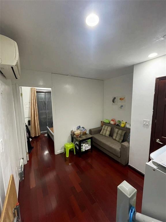 living room featuring wood finished floors and a wall mounted AC