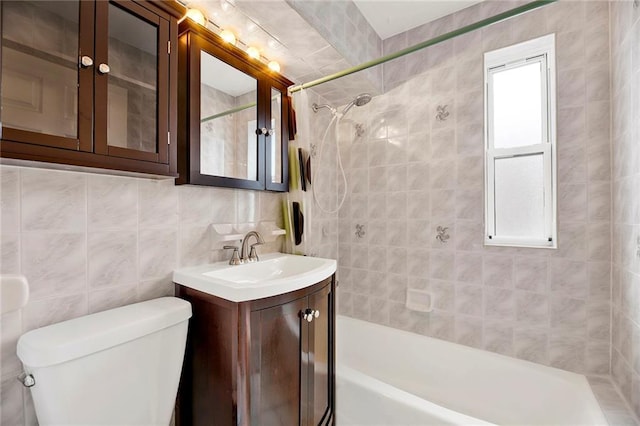 bathroom featuring tile walls, toilet, vanity, washtub / shower combination, and backsplash