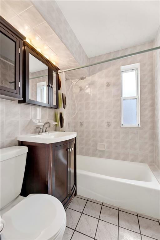 bathroom with toilet, vanity, tile patterned flooring, and tile walls