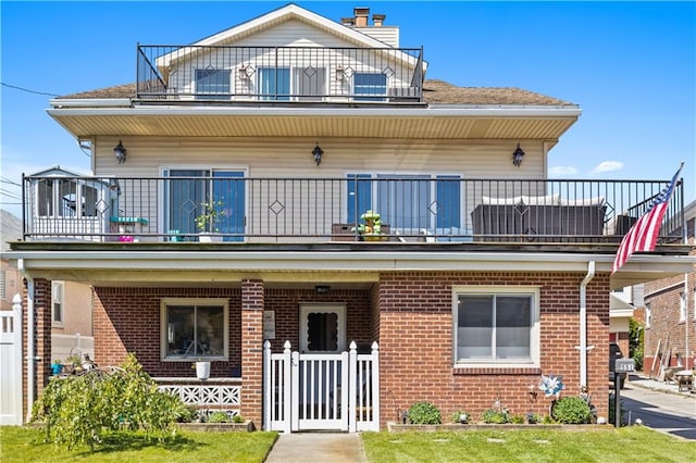 view of front facade featuring a balcony and brick siding