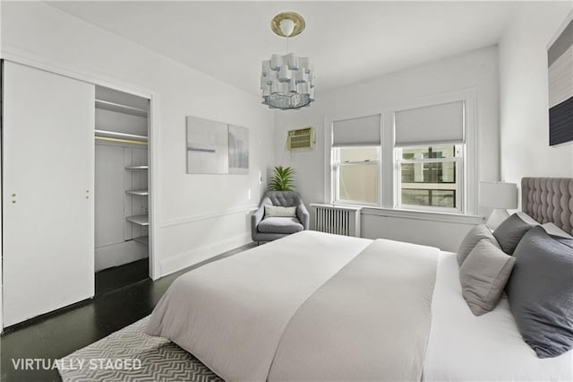 bedroom featuring dark wood-style flooring, baseboards, a closet, radiator heating unit, and a wall mounted air conditioner