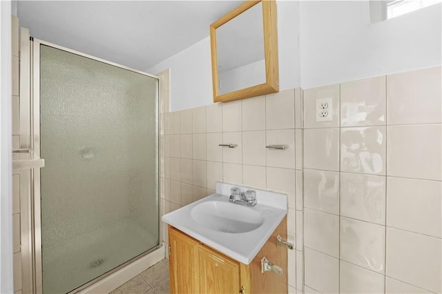 full bath featuring a stall shower, tile patterned flooring, vanity, and tile walls