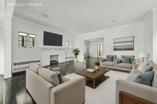 living area with crown molding, dark wood-style flooring, a fireplace, and radiator heating unit