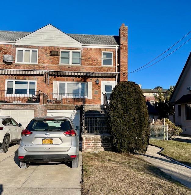 view of front facade with driveway, a chimney, roof with shingles, an attached garage, and brick siding