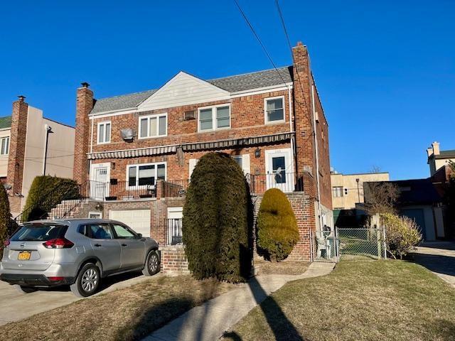 multi unit property featuring stairs, concrete driveway, brick siding, and a chimney