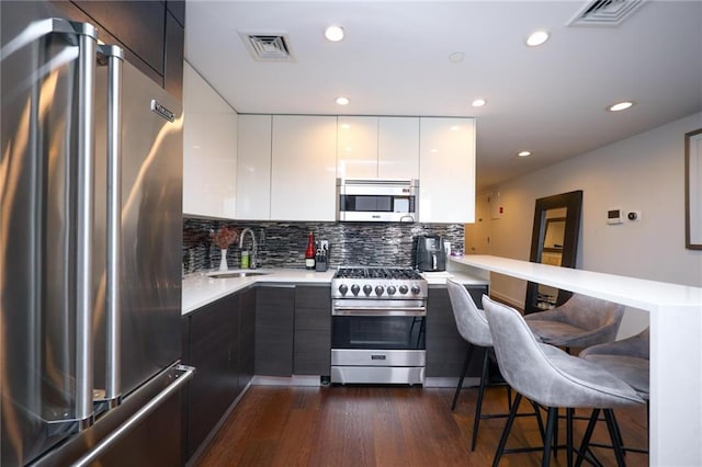 kitchen featuring stainless steel appliances, visible vents, a sink, modern cabinets, and a peninsula