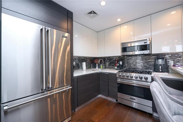 kitchen with visible vents, high end appliances, modern cabinets, light countertops, and a sink