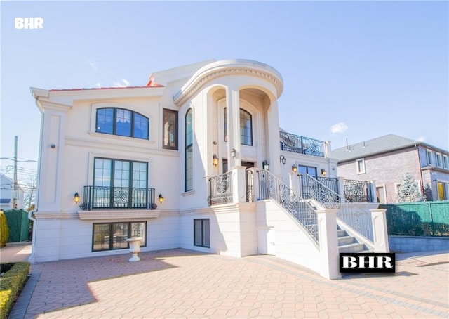 view of front of property featuring stucco siding, stairs, and a patio