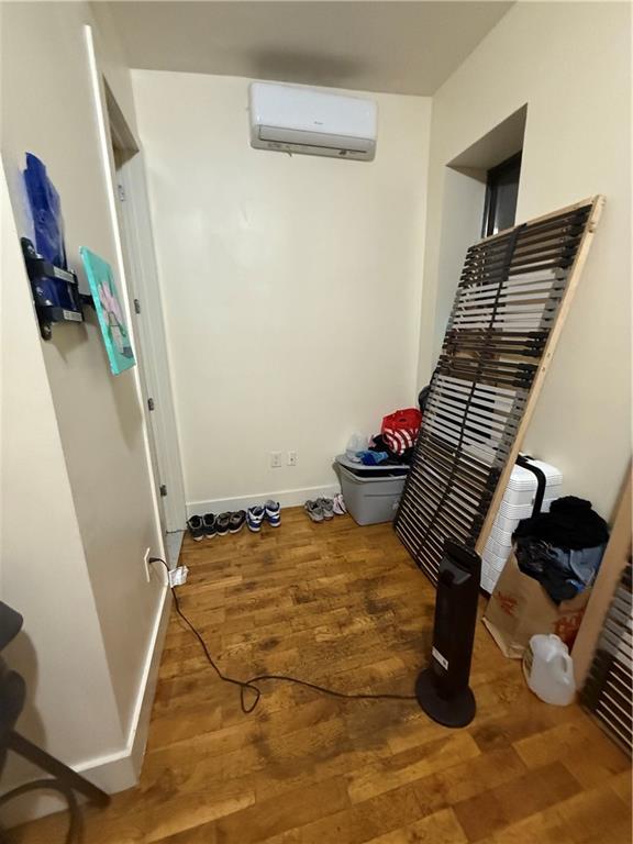 interior space featuring baseboards, an AC wall unit, and wood finished floors