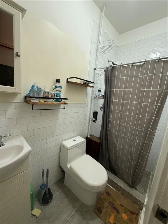 bathroom with toilet, a stall shower, tile patterned flooring, and tile walls