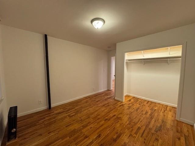 unfurnished bedroom with a closet, baseboards, and wood finished floors