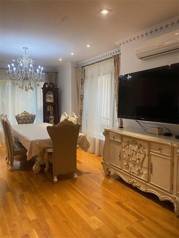 dining area featuring crown molding, light wood finished floors, a chandelier, and a wall mounted AC