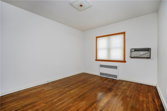 empty room featuring radiator, wood-type flooring, and baseboards