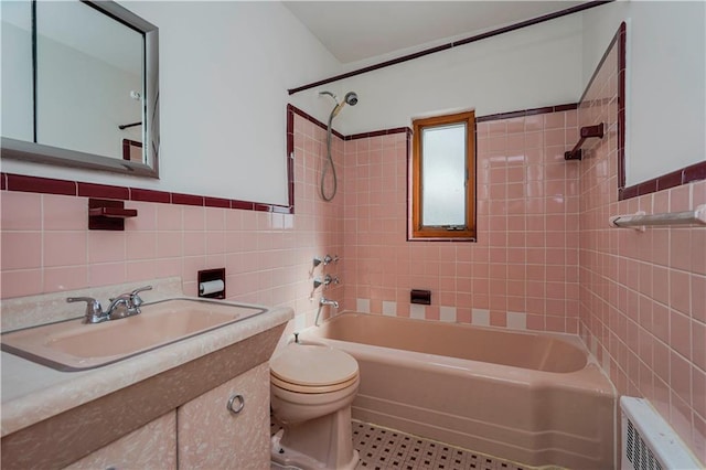 full bathroom featuring toilet, radiator heating unit, vanity, shower / washtub combination, and tile walls