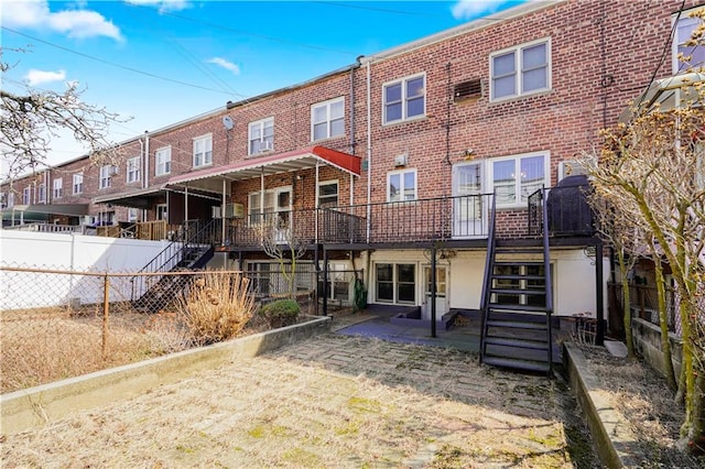 back of house with fence, stairway, and brick siding