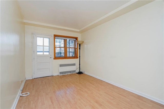 unfurnished room featuring radiator, light wood finished floors, baseboards, and ornamental molding