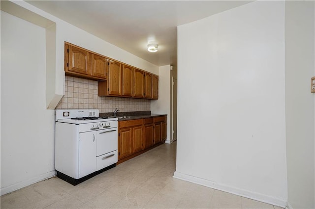 kitchen with a sink, baseboards, backsplash, brown cabinets, and gas range gas stove