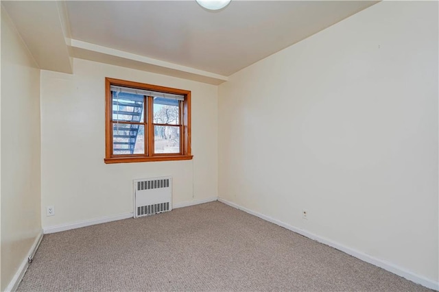 empty room with carpet floors, baseboards, and radiator heating unit