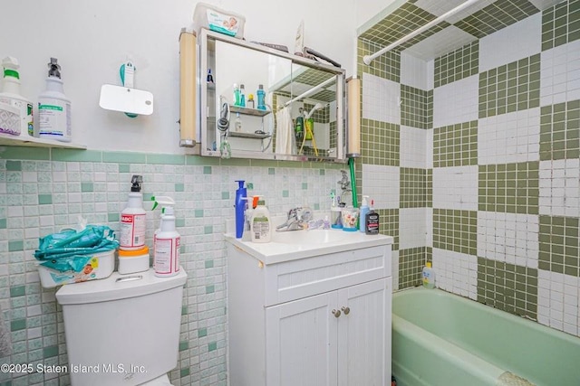 31 Seeley St, Brooklyn, NY 11218 - bathroom featuring vanity, toilet, washtub / shower combination, and tile walls