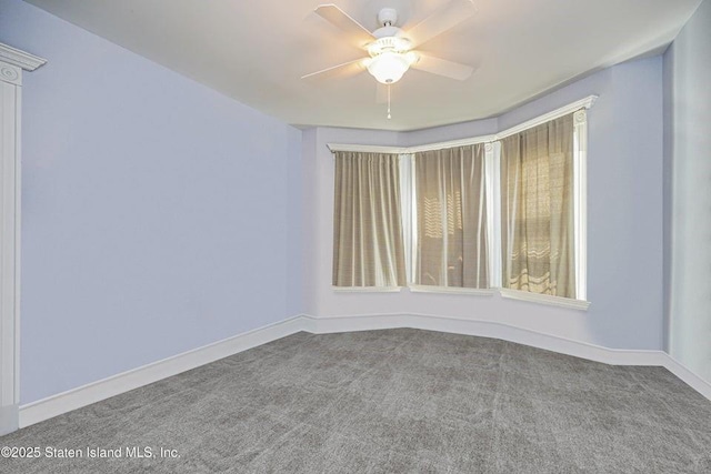 carpeted empty room with a ceiling fan and baseboards