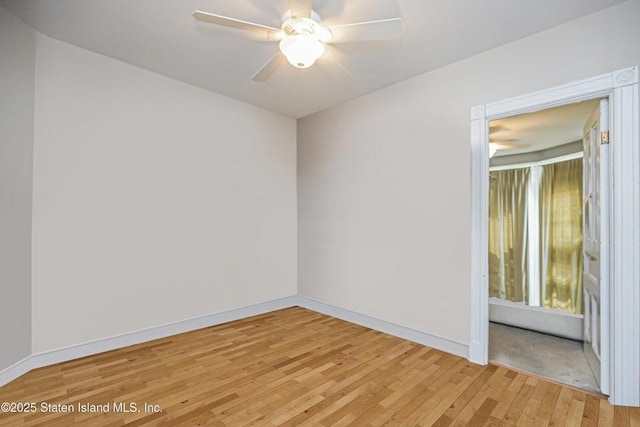 spare room featuring light wood finished floors, baseboards, and a ceiling fan