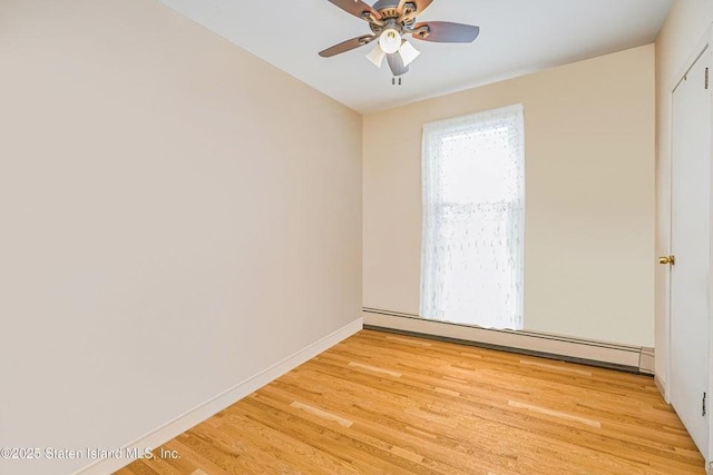 spare room featuring a baseboard radiator, baseboards, ceiling fan, and light wood finished floors