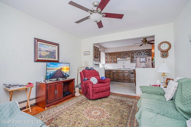 living room featuring a baseboard heating unit, ceiling fan, and wood finished floors