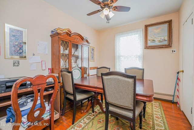 dining room featuring a baseboard radiator, a ceiling fan, and wood finished floors